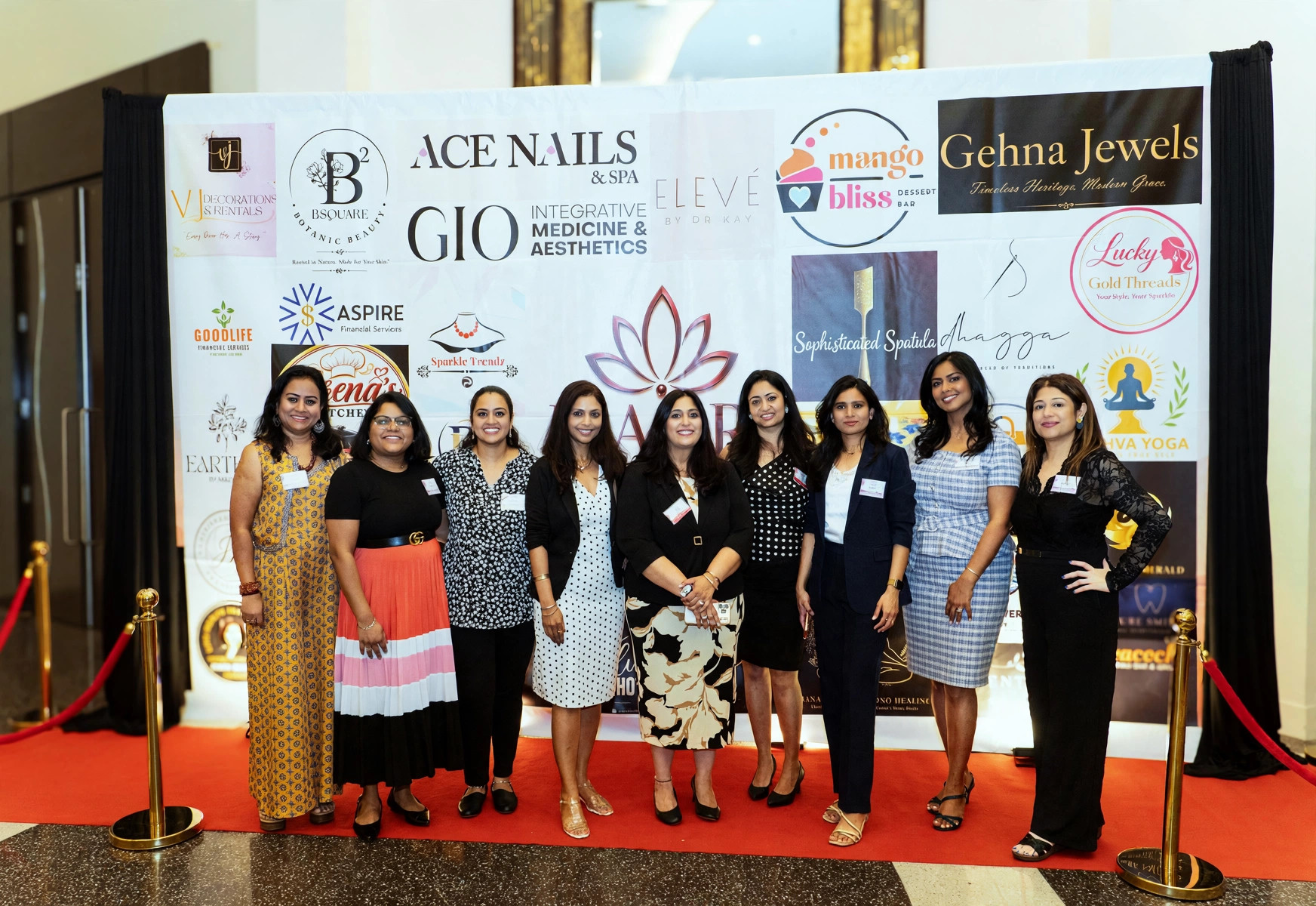 Twelve women together on the red carpet at the sponsor backdrop